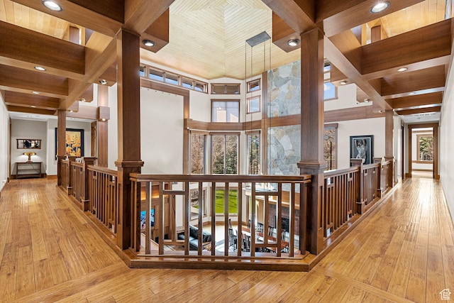 hall featuring hardwood / wood-style floors, ornate columns, a healthy amount of sunlight, and a towering ceiling