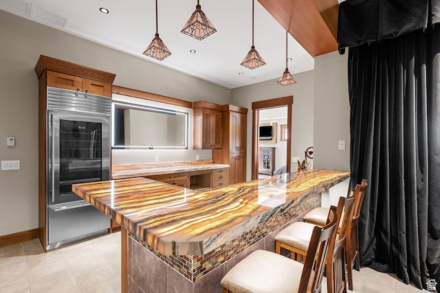 kitchen featuring brown cabinetry, light tile patterned flooring, recessed lighting, hanging light fixtures, and a kitchen breakfast bar