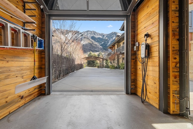 entryway featuring a mountain view, concrete flooring, and wood walls