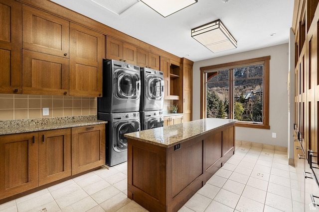 clothes washing area featuring light tile patterned floors, cabinet space, and stacked washer and clothes dryer
