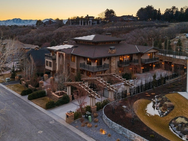 exterior space featuring concrete driveway, a balcony, a mountain view, and roof mounted solar panels