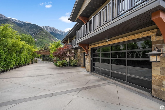 17 S Crosshill Ln, Sandy, UT 84092 - view of side of home with a balcony, stone siding, a mountain view, driveway, and an attached garage