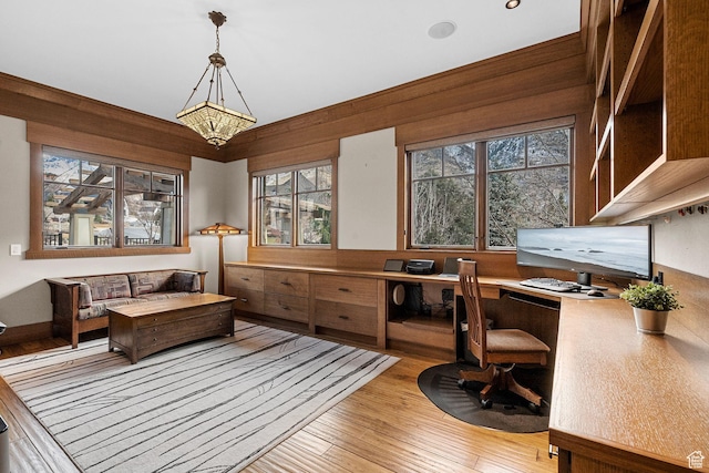 office area with a chandelier, built in desk, and light wood-style flooring