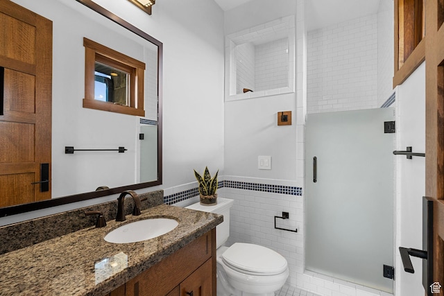 bathroom featuring vanity, a wainscoted wall, a shower stall, tile walls, and toilet