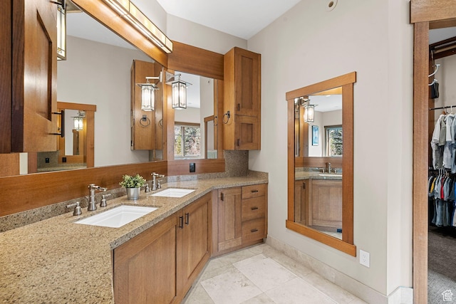 full bathroom with a sink, decorative backsplash, a spacious closet, and double vanity