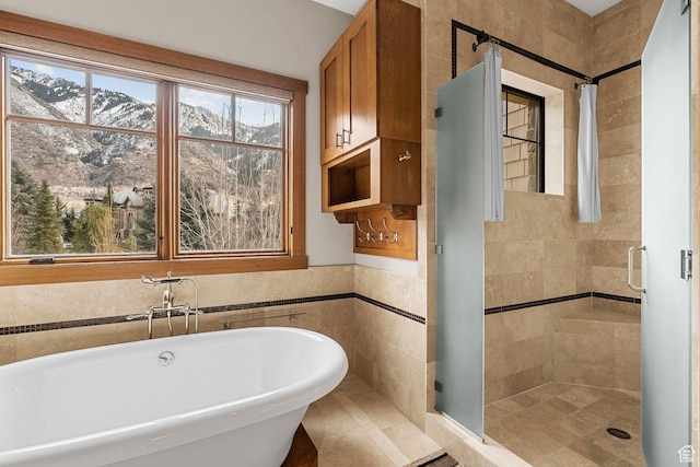 bathroom with a freestanding bath, a stall shower, and tile walls