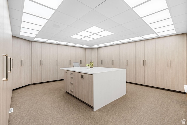 kitchen with a center island, light countertops, and a paneled ceiling