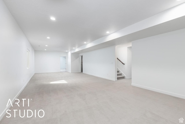 finished below grade area featuring light carpet, recessed lighting, stairs, and baseboards