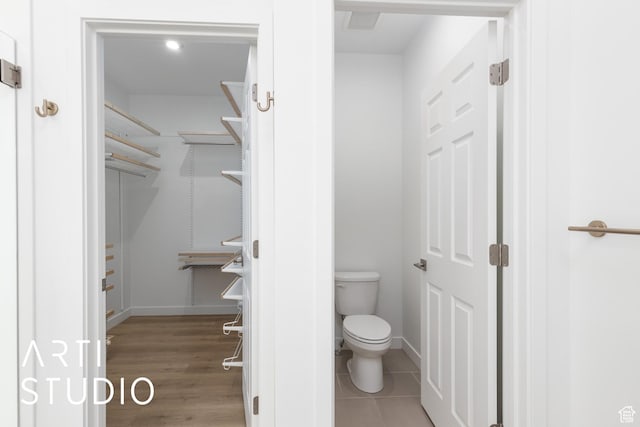 bathroom with toilet, wood finished floors, and baseboards