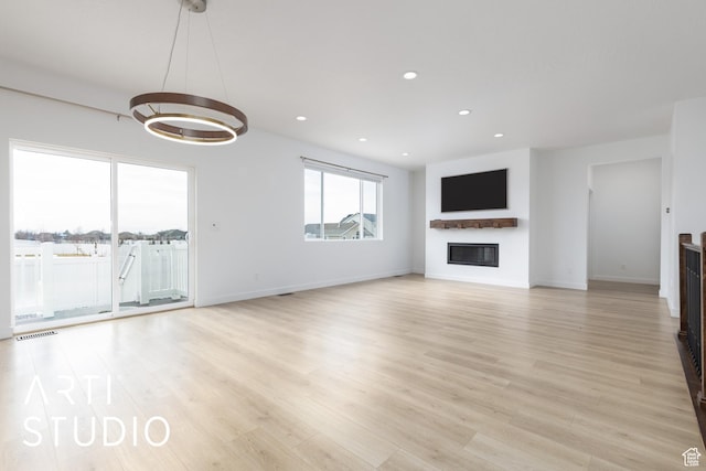 unfurnished living room featuring a glass covered fireplace, recessed lighting, and light wood finished floors