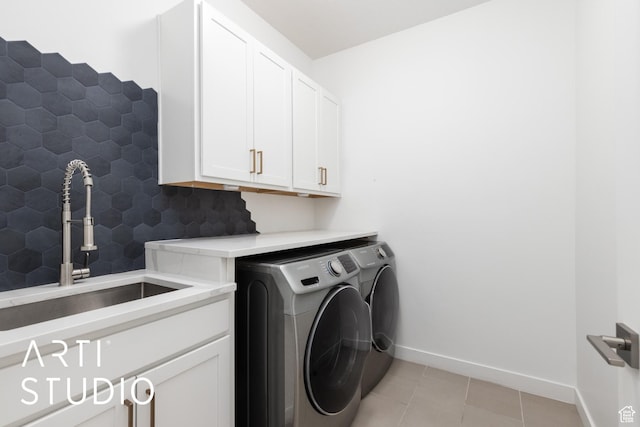 laundry room featuring baseboards, washing machine and dryer, light tile patterned floors, cabinet space, and a sink