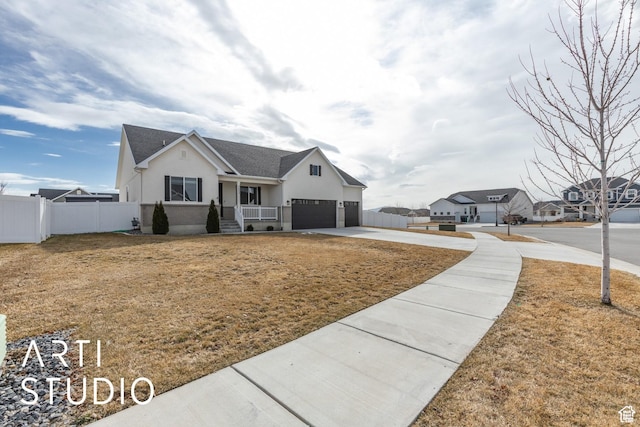 view of front of house featuring a front lawn, fence, driveway, and stucco siding