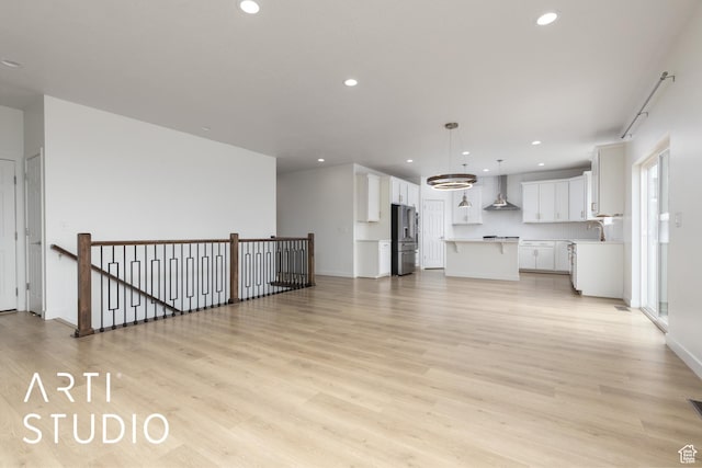 unfurnished living room with light wood finished floors, recessed lighting, and a sink