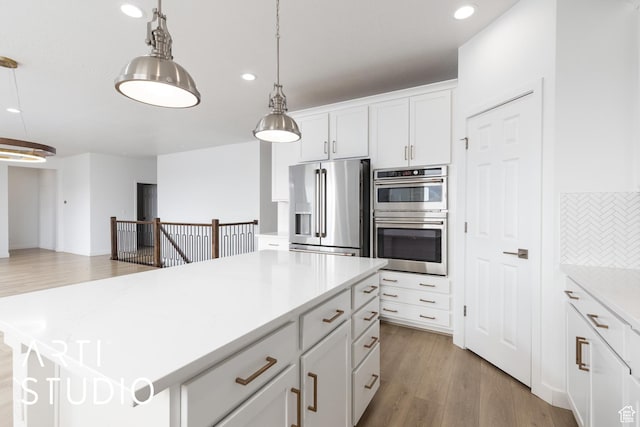 kitchen with a center island, pendant lighting, light wood-style flooring, white cabinets, and stainless steel appliances