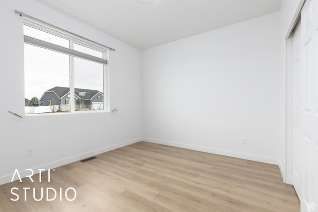 unfurnished bedroom with light wood-type flooring, visible vents, baseboards, and a closet