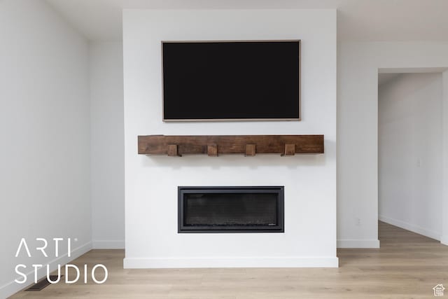 interior details with a glass covered fireplace, baseboards, and wood finished floors