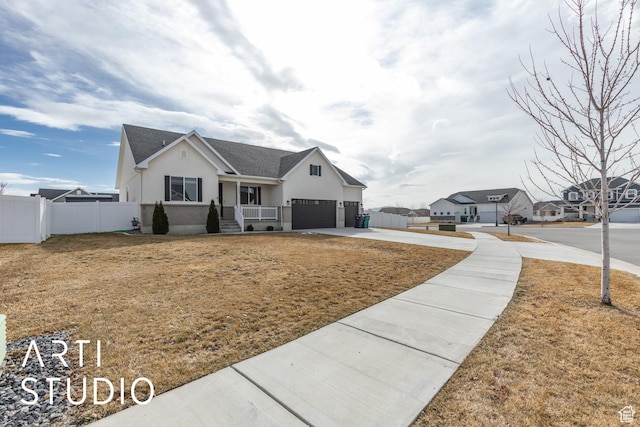 view of front facade featuring stucco siding, concrete driveway, a front yard, and fence