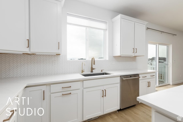 kitchen featuring white cabinetry, light wood-style flooring, a sink, decorative backsplash, and dishwasher