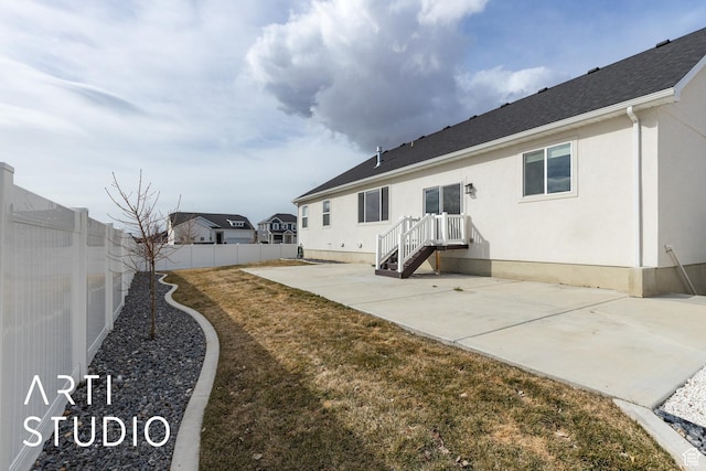 back of property with stucco siding, a patio, roof with shingles, and a fenced backyard