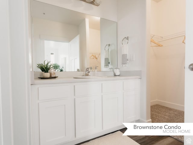 bathroom with a spacious closet, baseboards, and vanity