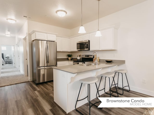 kitchen featuring visible vents, appliances with stainless steel finishes, white cabinets, a peninsula, and a kitchen bar