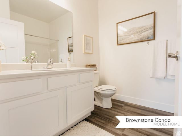 bathroom featuring baseboards, vanity, toilet, and wood finished floors