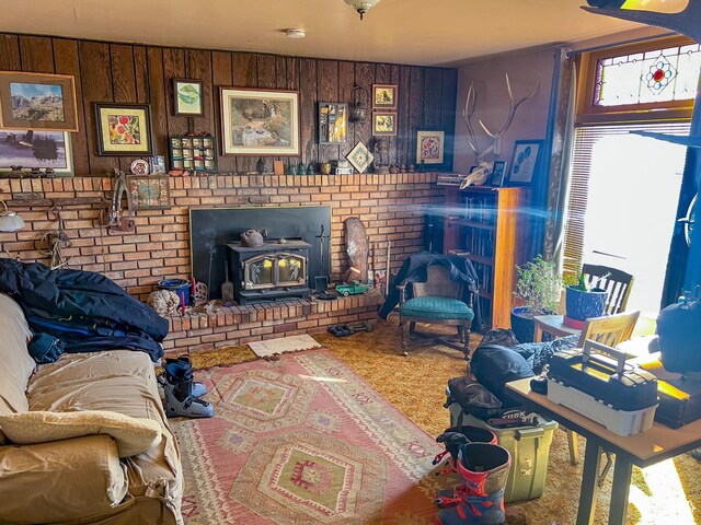 carpeted living room featuring wood walls and a wood stove