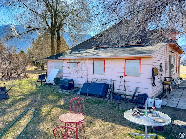 rear view of property featuring a lawn and a shingled roof