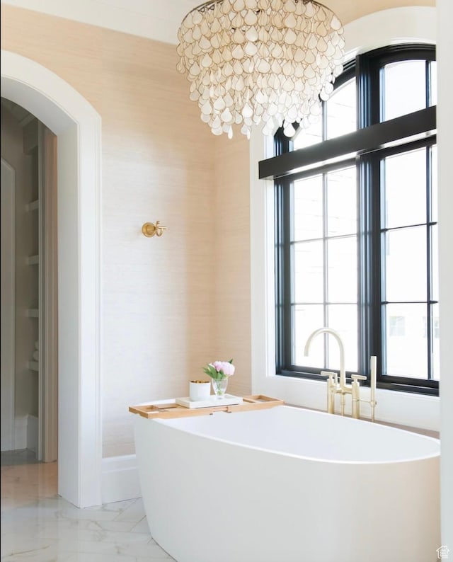 bathroom with marble finish floor, a soaking tub, and a sink