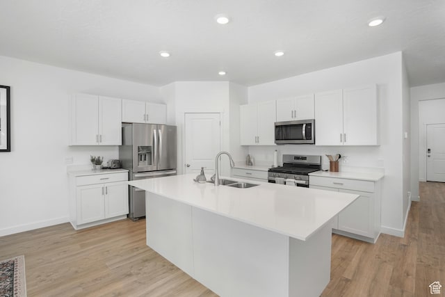 kitchen featuring stainless steel appliances, light countertops, a sink, and an island with sink