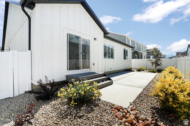 rear view of house featuring a patio area, a fenced backyard, and board and batten siding