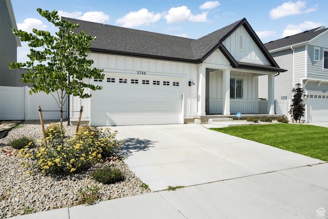 modern farmhouse featuring an attached garage, a shingled roof, fence, concrete driveway, and board and batten siding