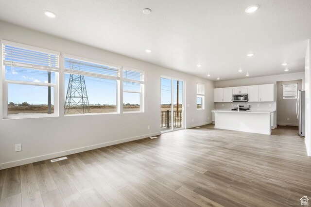 3537 S 3150 W Unit 106, West Haven, UT 84401 - unfurnished living room featuring baseboards, visible vents, light wood-style flooring, and recessed lighting