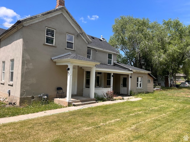 view of front of property with a front yard, roof with shingles, a chimney, and stucco siding