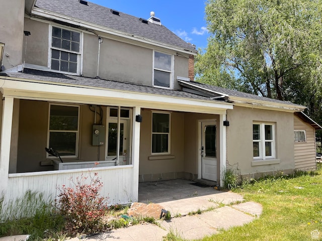 rear view of house featuring a shingled roof, a chimney, and a patio