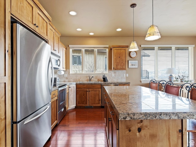kitchen with stainless steel appliances, dark wood-type flooring, a kitchen island, a sink, and decorative backsplash