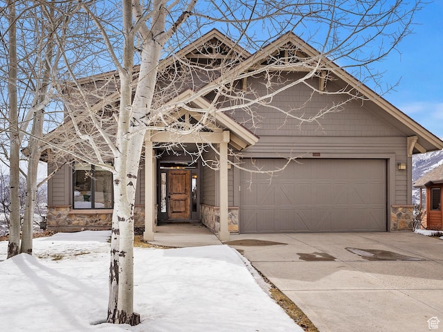 view of front of house featuring an attached garage, stone siding, and concrete driveway