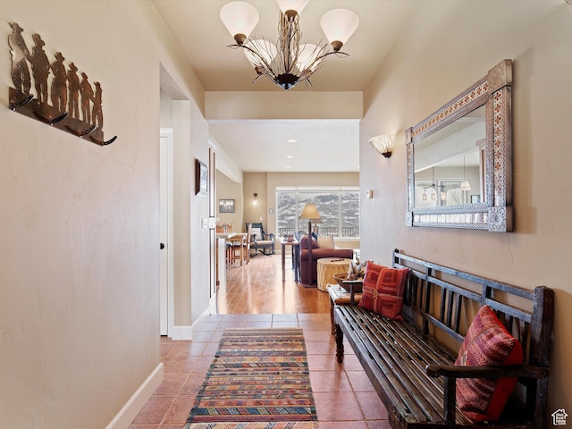 hallway with baseboards, tile patterned flooring, and a notable chandelier