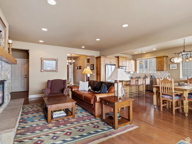 living room featuring recessed lighting, a stone fireplace, an inviting chandelier, and wood finished floors