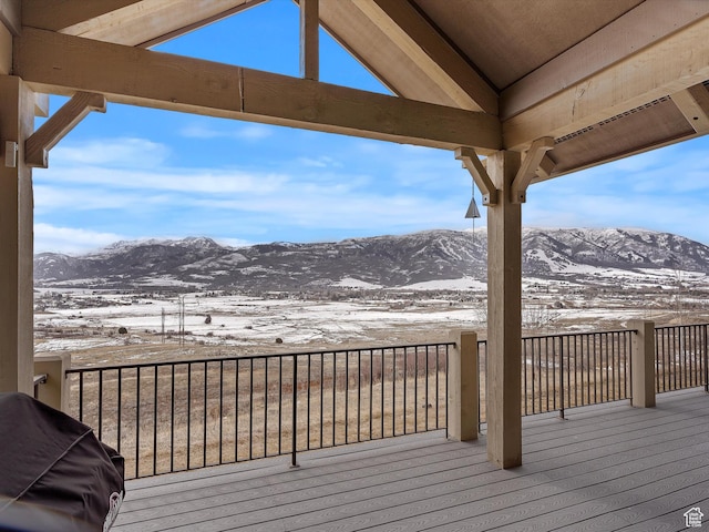 snow covered deck with a mountain view and area for grilling