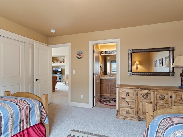 carpeted bedroom featuring ensuite bath, baseboards, and a closet