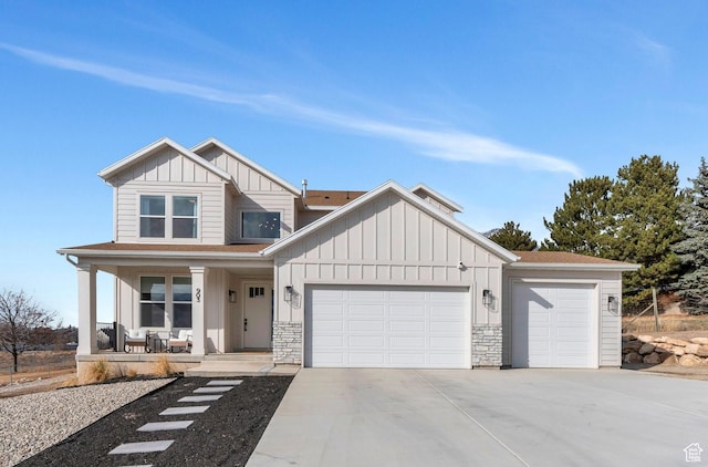view of front of home with a garage, covered porch, driveway, stone siding, and board and batten siding