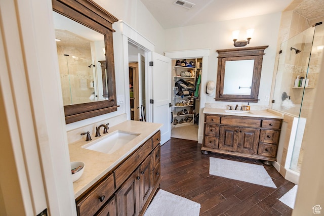 bathroom with two vanities, a sink, visible vents, hardwood / wood-style floors, and a stall shower