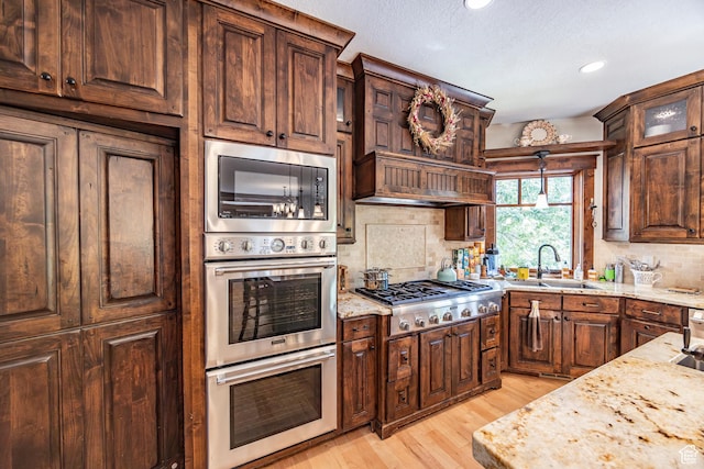 kitchen featuring light stone countertops, appliances with stainless steel finishes, decorative backsplash, and a sink