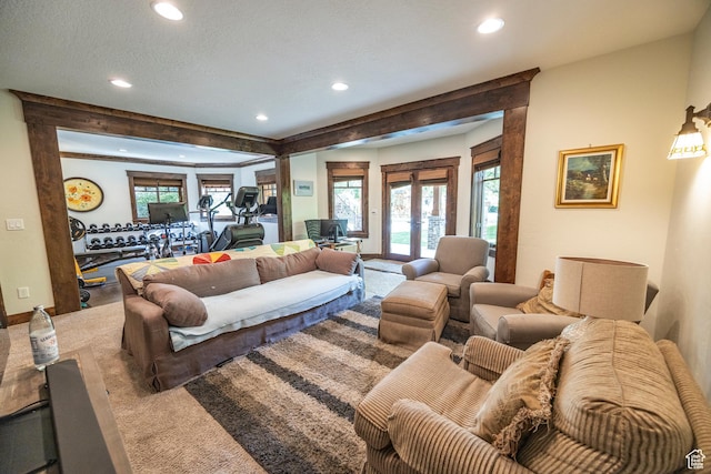 carpeted living area featuring recessed lighting, french doors, a textured ceiling, and baseboards