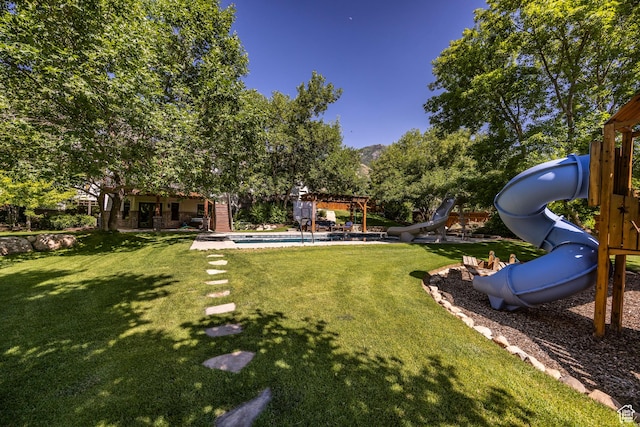 view of yard with a pergola, an outdoor pool, and a playground