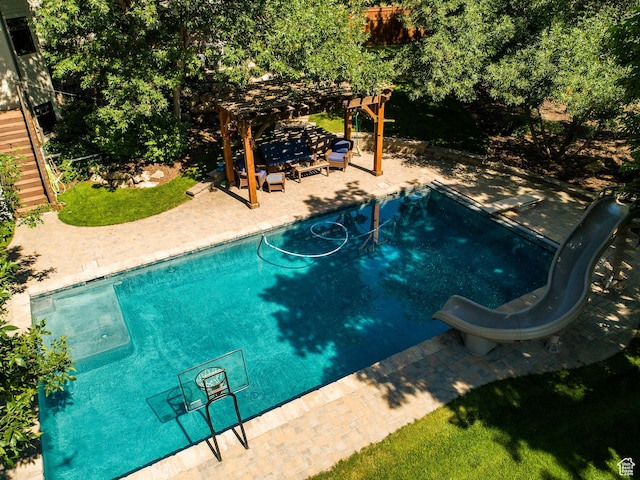 pool with a water slide, a patio area, and a pergola