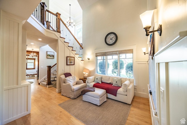 living room featuring a chandelier, a decorative wall, stairs, and light wood-style floors