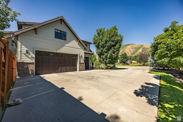 view of side of property featuring concrete driveway, brick siding, and a mountain view