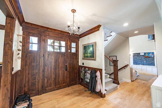 entryway with a chandelier, wood walls, stairway, and light wood finished floors